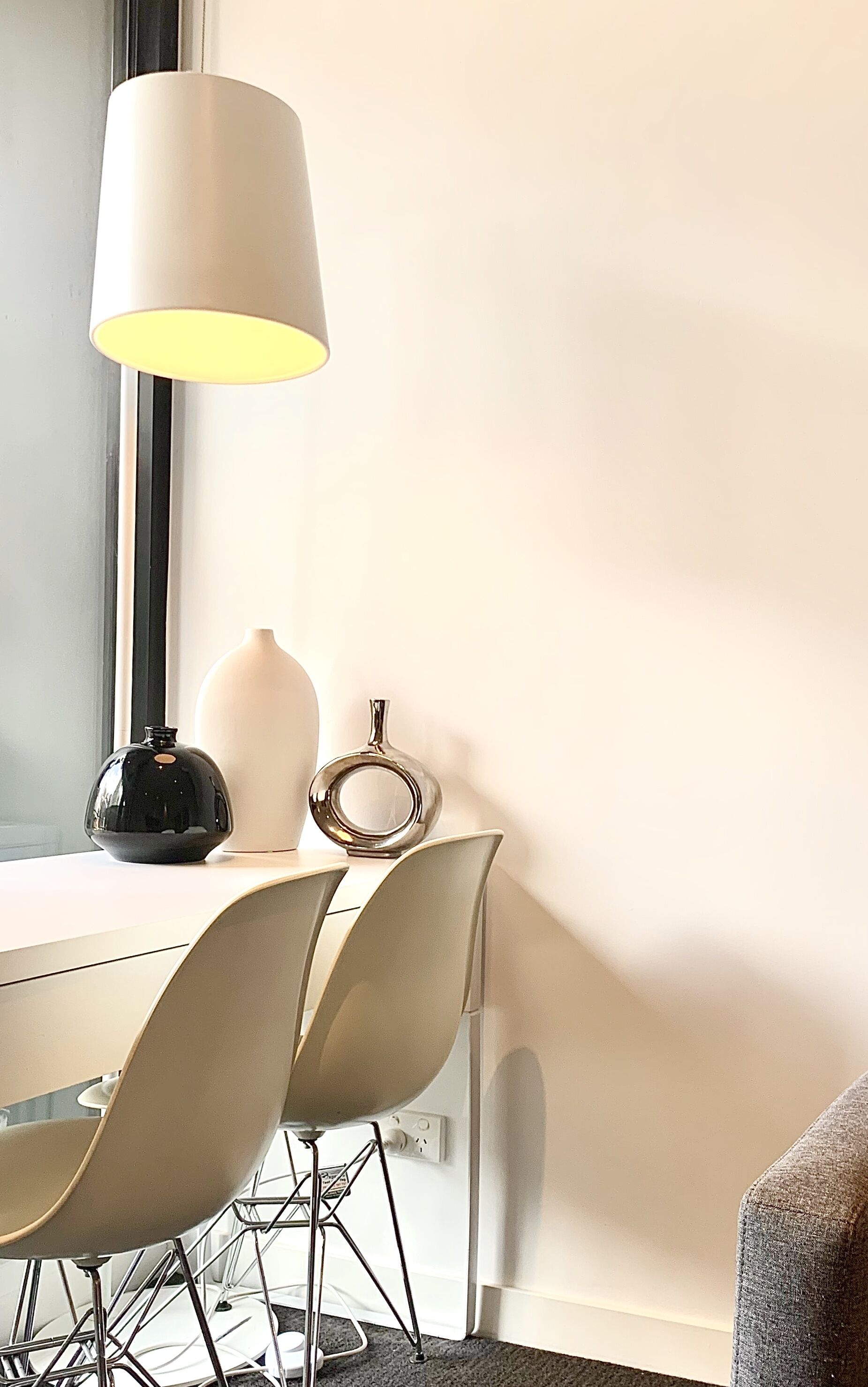Et moderne spiseområde med et bord, stole, en lampe og dekorative vaser.