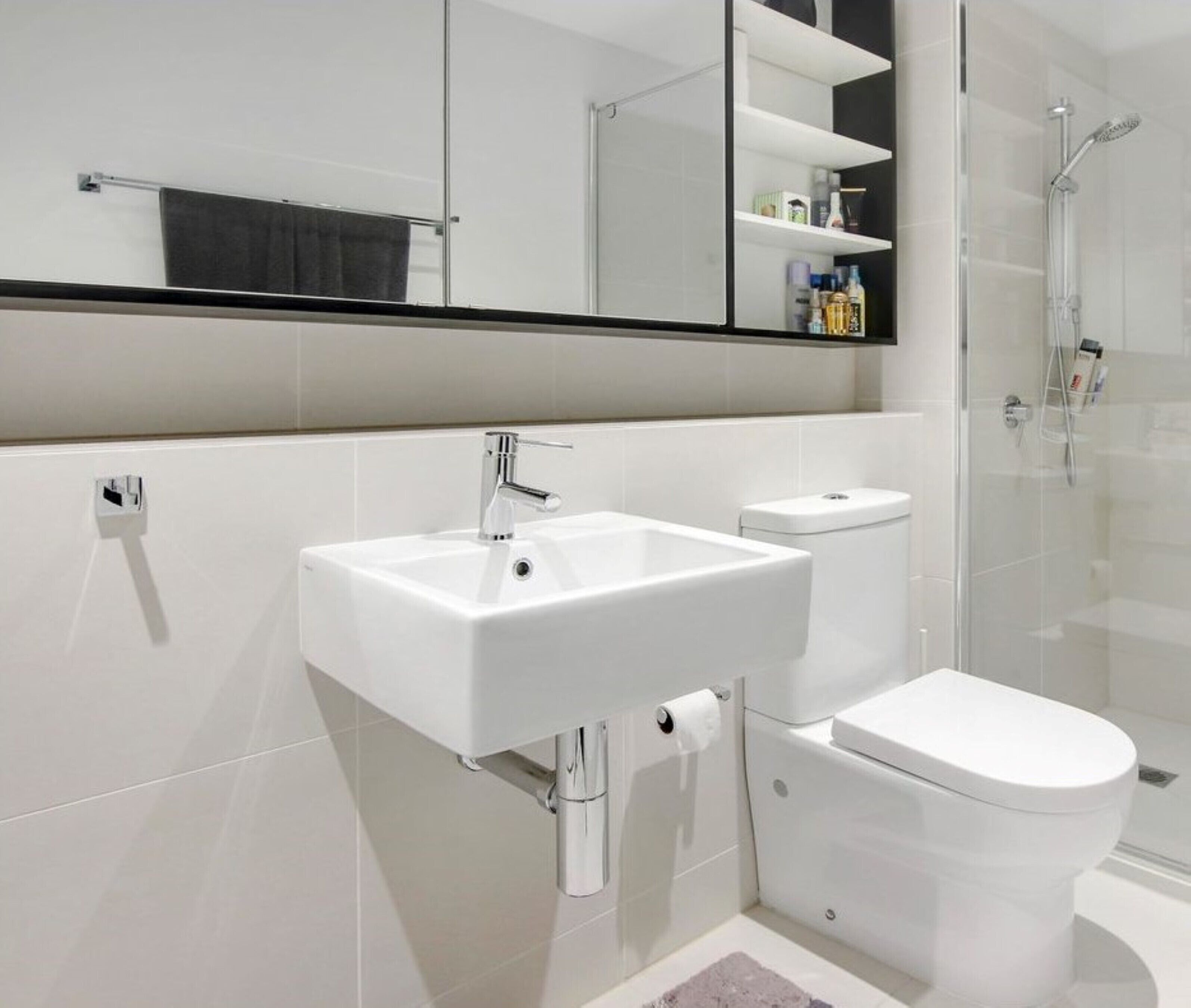 Un baño moderno con lavamanos, inodoro y cabina de ducha de vidrio.