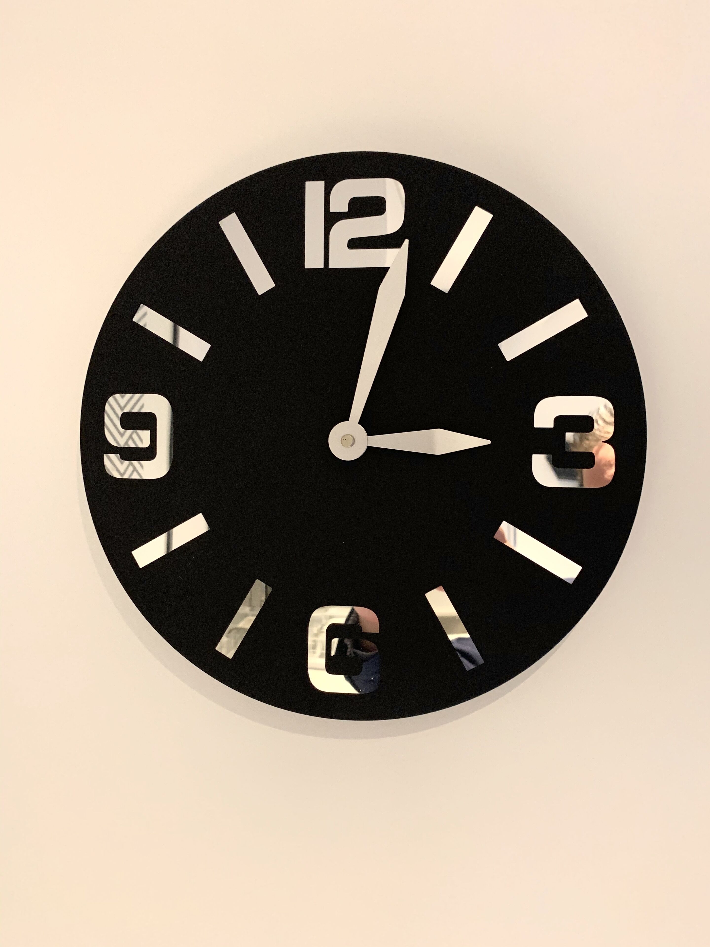 Eine runde Wanduhr mit schwarzem Zifferblatt und weißen Zahlen.