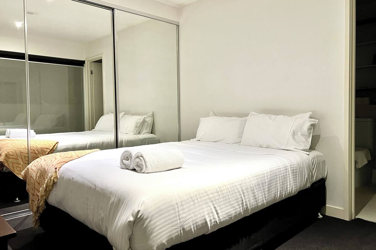 A hotel room with a large bed, a separate seating area, and a mirrored closet.
