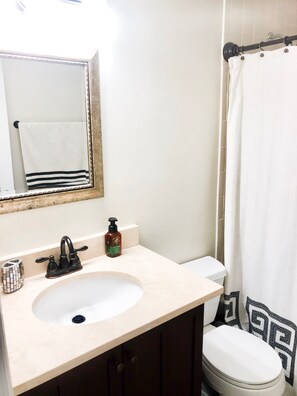 A bathroom with a sink, mirror, toilet, and shower curtain. - Masters Rental 2020! (Augusta)