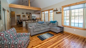 A spacious living area with a large gray sectional sofa, a patterned armchair, and a wooden floor. - Beautiful New Home!! (Intervale)