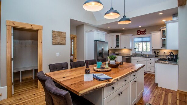 A spacious kitchen with white cabinets, a wooden dining table, and pendant lighting. - Beautiful New Home!! (Intervale)