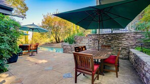 An outdoor patio with a pool, stone walls, and wooden furniture. - Sebastopol Luxury Home With Views, Pool & Hot tub (Sebastopol)