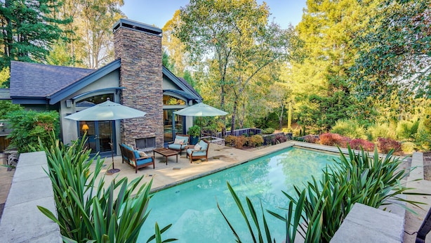 Uma casa moderna com lareira de pedra, piscina e mobiliário de exterior.