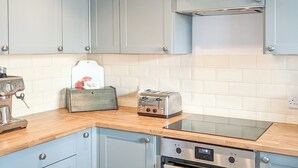 A kitchen with light blue cabinets, a wooden countertop, a coffee machine, a toaster, and an oven. - 3 bedroom accommodation in Sheringham (Sheringham)