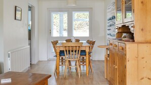 A dining area with a wooden table and chairs, a buffet cabinet, and a view through the door. - 3 bedroom accommodation in Sheringham (Sheringham)