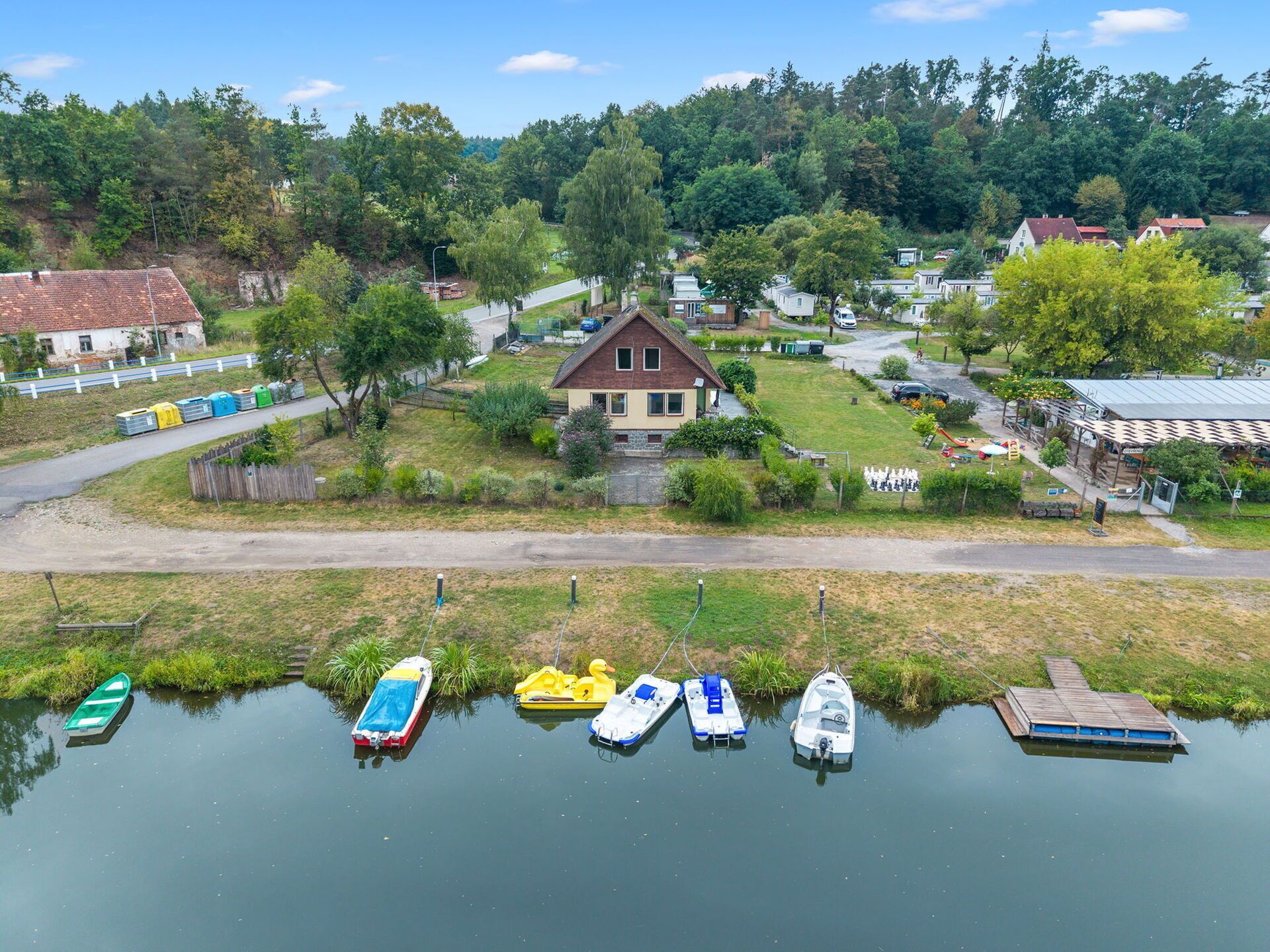 A lakeside property with a house, docked boats, and a road leading to the house.