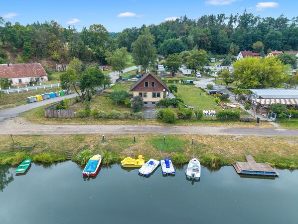 A lakeside property with a house, docked boats, and a road leading to the house.