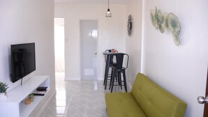 Un salon comprenant un téléviseur, un canapé et un coin repas avec des chaises et une table.
