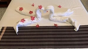 Un lit bien fait, avec du linge de lit blanc et une disposition décorative des serviettes en forme de cygnes.