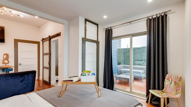 A bedroom with a bed, a desk, a chair, and a view of the outdoors.