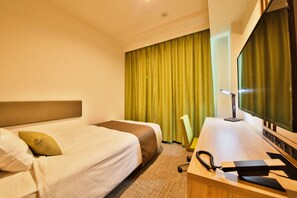 Une chambre d’hôtel avec un lit, un bureau avec un ordinateur et une télévision.