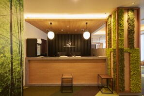 Un comptoir d’accueil avec un revêtement en bois, deux lampes suspendues rondes et un logo au-dessus du comptoir.