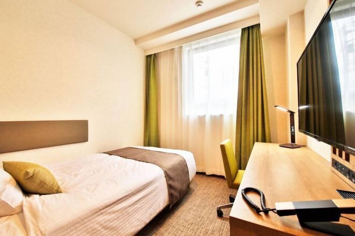 A hotel room with two beds, a desk with a computer, and a TV.