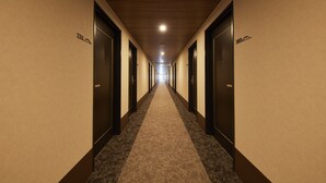 A hotel hallway with carpeted floors, wooden ceiling, and doors marked with room numbers.