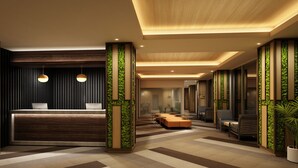 A modern hotel lobby with a reception desk, seating area, and decorative green vertical panels.