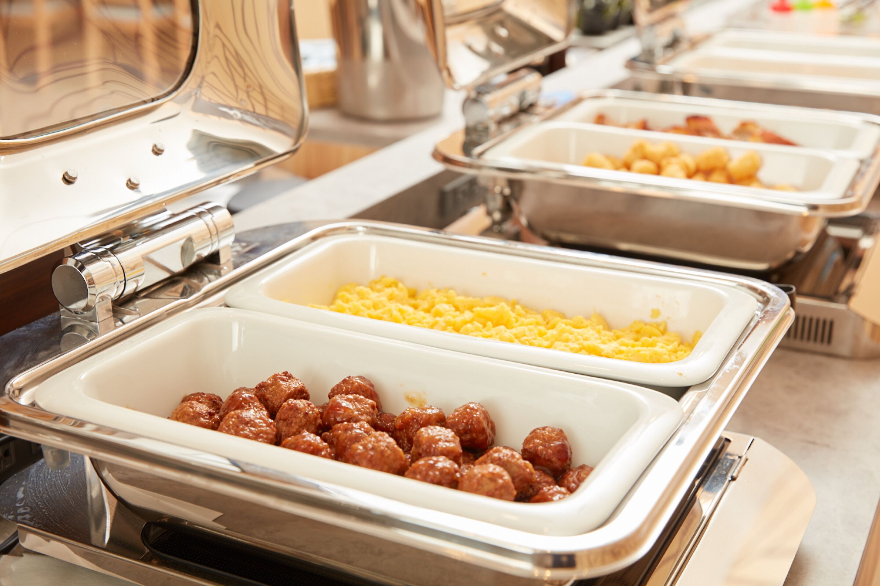 A buffet with multiple serving stations, including trays of meatballs and macaroni.