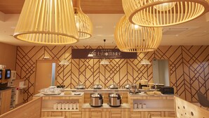 A restaurant interior with wooden paneling, hanging pendant lights, and a counter displaying various dishes and utensils.