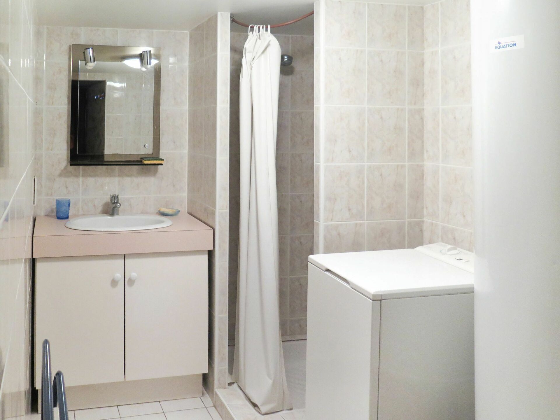 A bathroom with a sink, mirror, cabinet, shower curtain, and a towel rack.