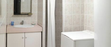 A bathroom with a sink, mirror, cabinet, shower curtain, and a towel rack.