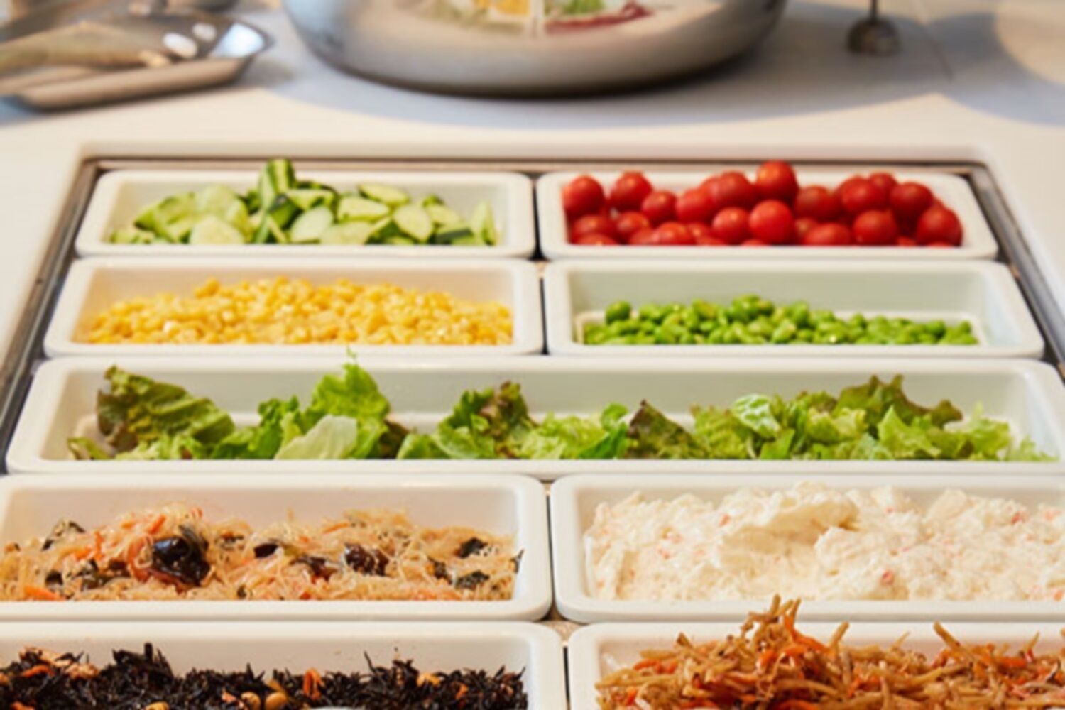 Buffet com diversos pratos, incluindo saladas, frutas e opções de arroz.
