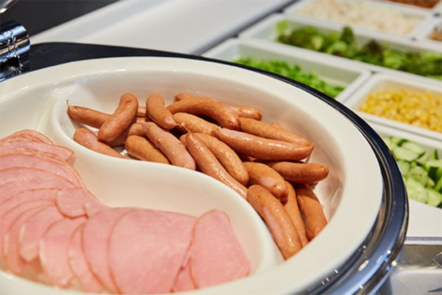 A buffet with sliced ham and sausages.
