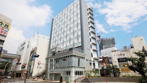 A modern hotel with a glass facade, multiple floors, and a prominent signage. - Rembrandt Style Honatsugi (Atsugi)