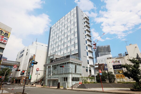 A modern hotel with a glass facade, multiple floors, and a prominent signage. - Rembrandt Style Honatsugi (Atsugi)