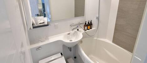 A modern bathroom with a white sink, mirror, and bathtub.