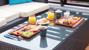 A dining table with two trays of food, a glass of orange juice, and a coffee cup.