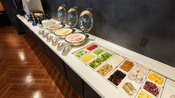Disposição de buffet com diversos alimentos e acompanhamentos.