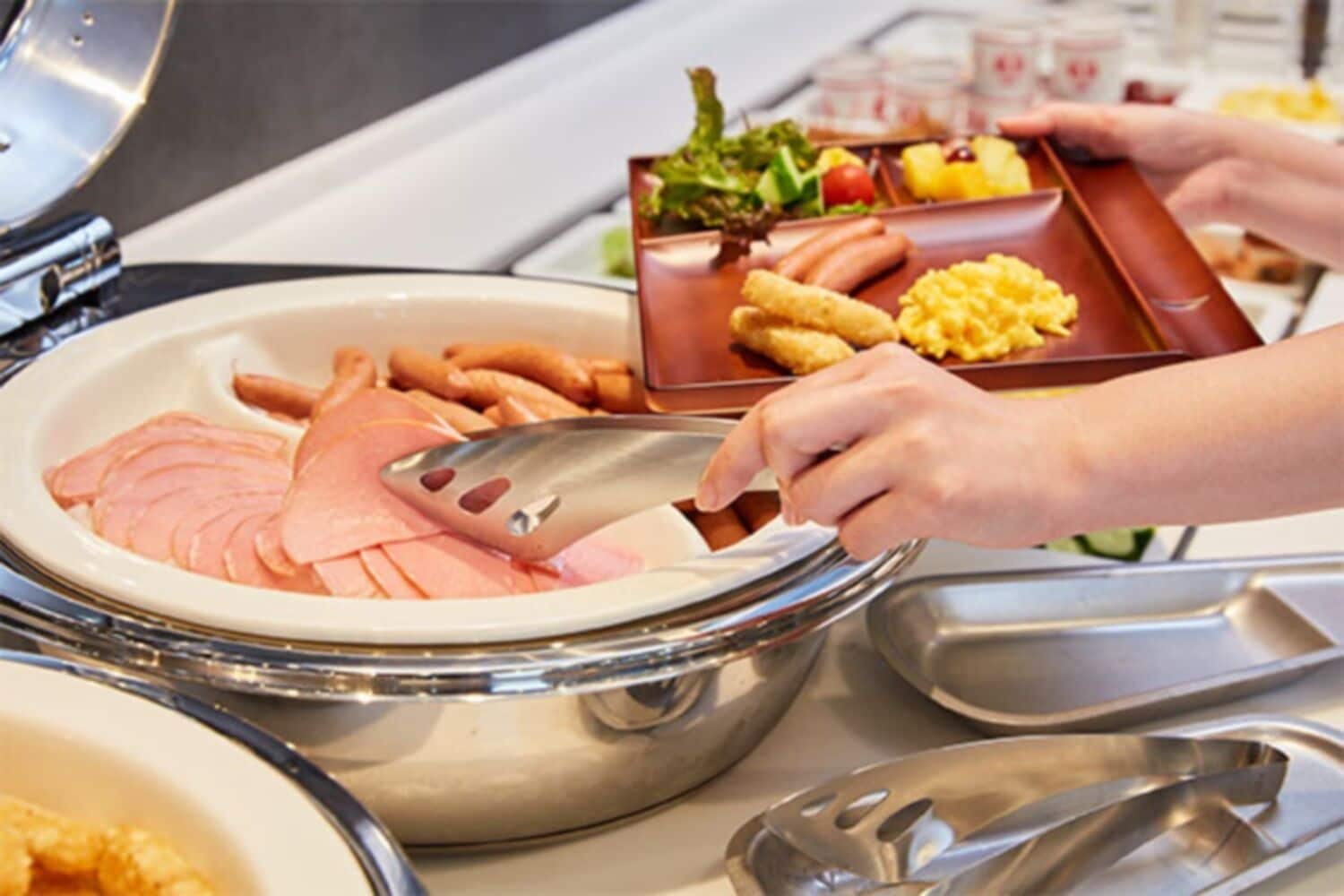 Ein reichhaltiges Buffet mit verschiedenen Speisen, darunter Schinken, Eier und Gemüse.
