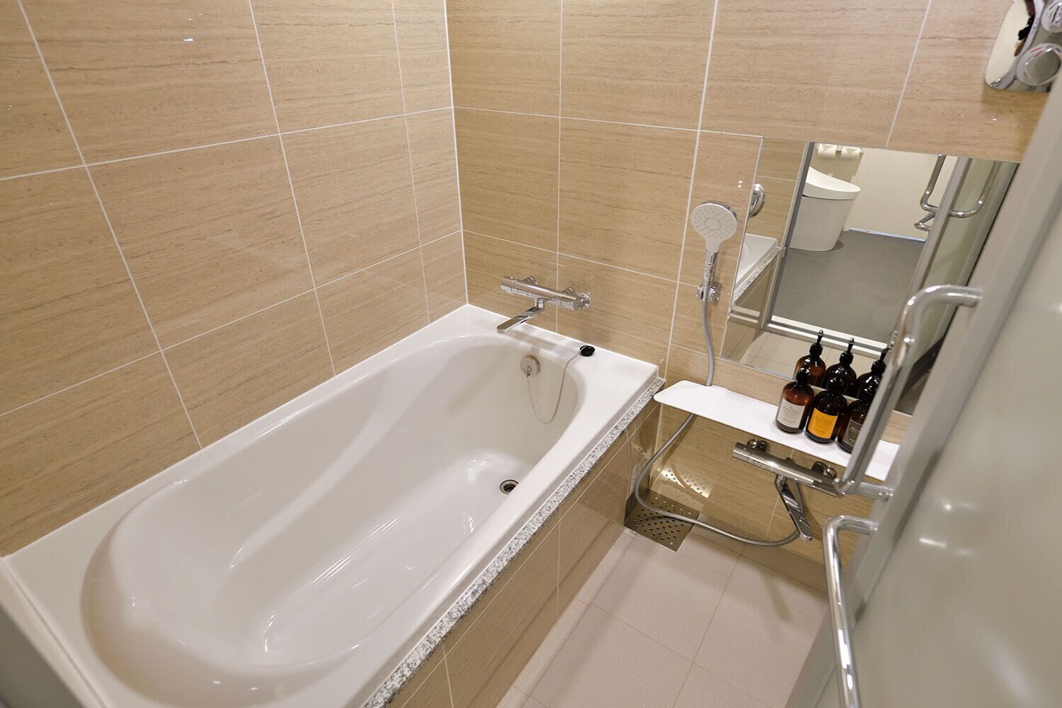 A bathroom with a white bathtub, a shower, and a vanity with toiletries.