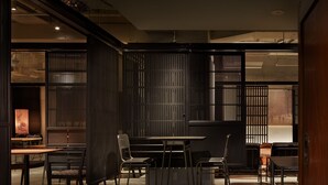 Un interior moderno con comedor, que incluye una mesa y sillas, zona de cocina con estufa, y vista al exterior a través de una ventana.