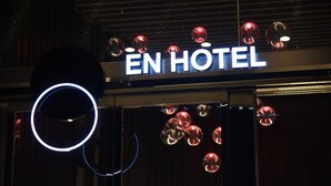 Un letrero de hotel con el nombre 'EN HOTEL' y luces esféricas decorativas.