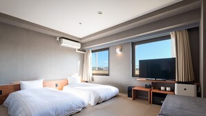 Habitación de hotel con dos camas, televisión y un ventanal con vistas.