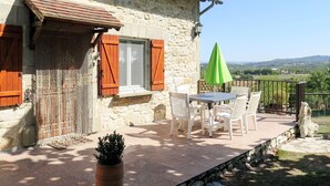 A stone building with a patio area featuring a table and chairs, a green umbrella, and a view of the countryside. - Stunning private villa for 5 guests with private pool, A/C, TV, terrace and panoramic view (La Grèze)