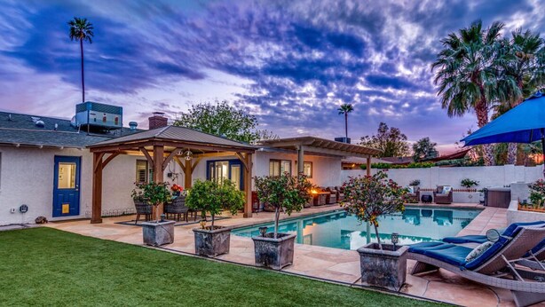 Un jardin avec une piscine, du mobilier d’extérieur et un patio couvert.