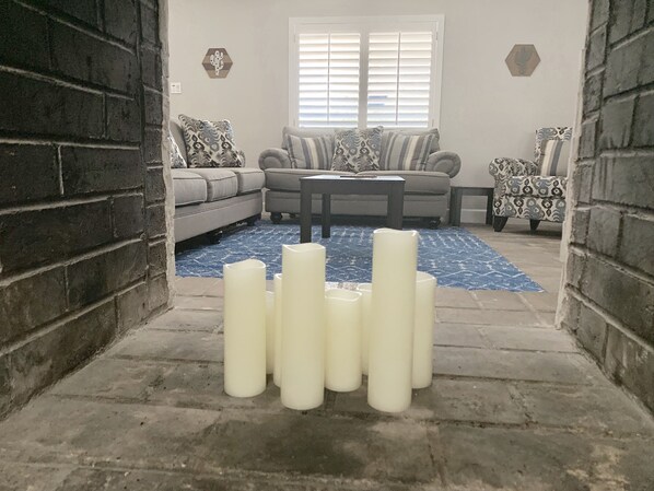 A living room with a sofa, a coffee table, and decorative pillows. There are several white cylindrical objects in the foreground.