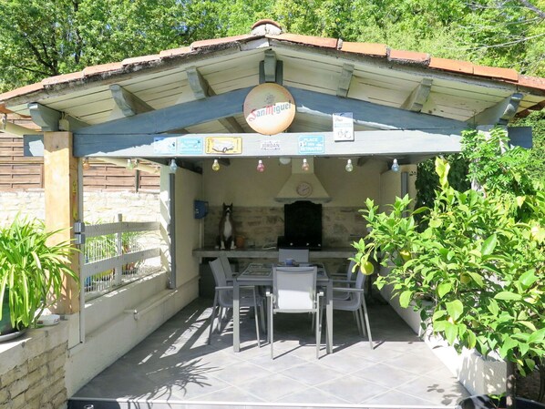 An outdoor patio with a table and chairs, a hanging sign, and a brick wall.