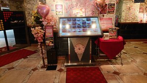 A hotel reception area with a digital display, floral decorations, and a red carpet. - Hotel Zips - Adults Only (Kawaguchi)