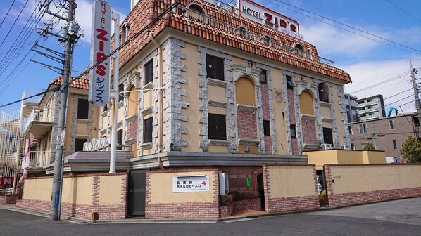 Um hotel com uma placa indicando "HOTEL ZIPS" e uma placa que sinaliza a entrada do saguão.