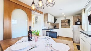 Une cuisine moderne avec des meubles en bois, une table à manger dressée avec des assiettes et des couverts, et des luminaires suspendus.