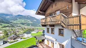 Un immeuble à plusieurs étages doté d’un balcon, offrant une vue sur une vallée et sur des montagnes en arrière-plan.