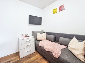 A modern living room with a grey sofa, a white dresser, and a flat-screen TV mounted on the wall. - Lovely apartment for 3 people with WIFI, TV and balcony (Untermärz)