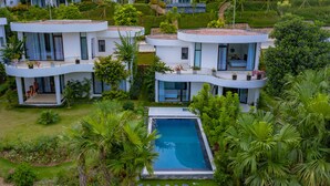 Un resort moderno con varias edificaciones blancas, una piscina central y abundante vegetación.