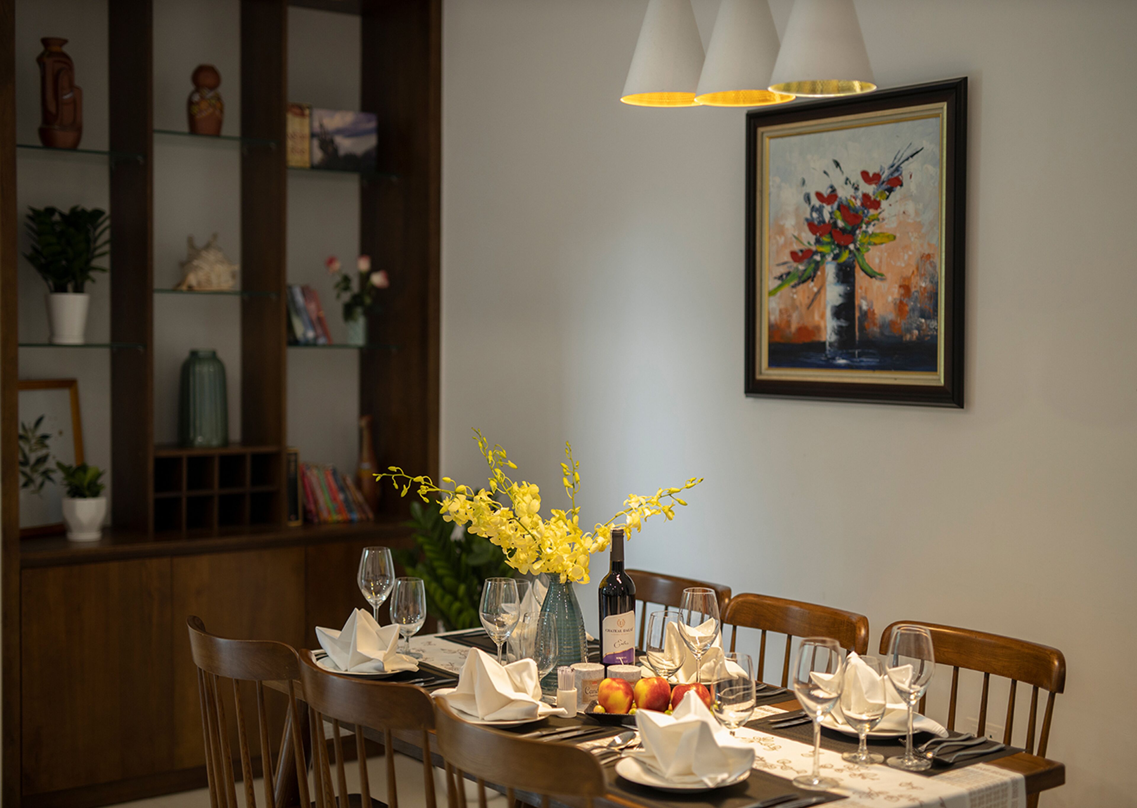A dining table set with plates, glasses, and a vase of yellow flowers.