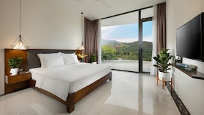 Un dormitorio de hotel moderno con una cama grande, un televisor de pantalla plana y un balcón con vistas panorámicas.