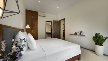A modern bedroom with a large bed, wooden wardrobe, and a ceiling fan.